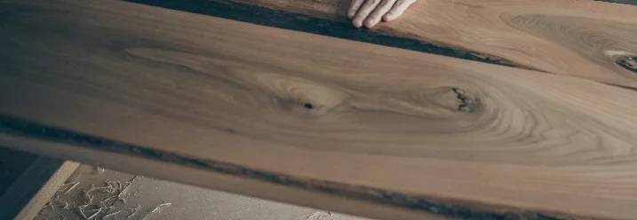 Person berührt eine große Holzplatte